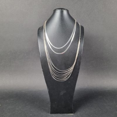 un gros plan d'un collier porté par un mannequin posé sur un présentoir