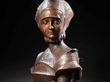 a bronze bust of a woman wearing a hat and holding a book