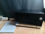 a black microwave sitting on a wooden table next to a window