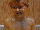 une statue en bois représentant un garçon, exposée dans une vitrine