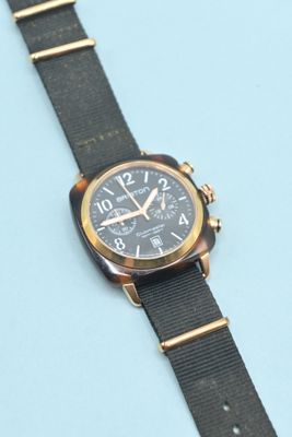 une image montrant un gros plan d'une montre posée sur une surface bleue