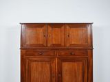 une vieille armoire en bois dans une pièce aux murs blancs