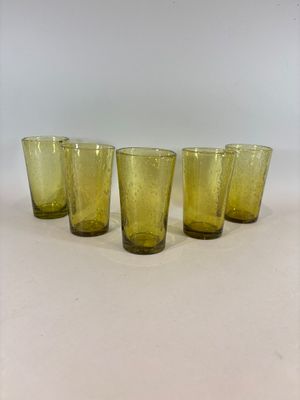 quatre verres jaunes alignés sur une surface blanche