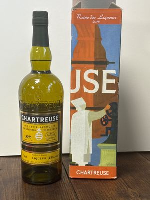 une bouteille de Chartreuse posée à côté d'une boîte sur une table