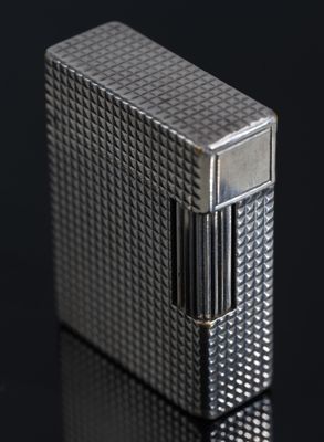 un gros plan d'un briquet argenté posé sur une surface noire