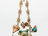 an image of a gold necklace with a bird and a bell hanging from it ' s chain