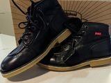 pair of black leather boots sitting on top of a white table