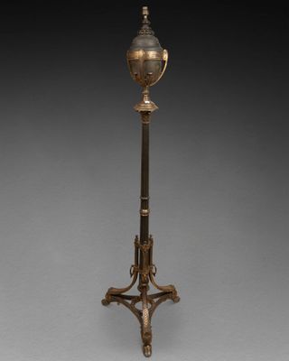 une lampe ancienne en laiton montée sur un trépied et dotée d'un abat-jour en verre