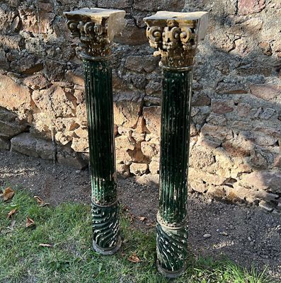 deux socles verts et dorés devant un mur de pierre