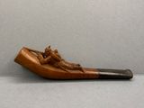 une pipe en bois sur laquelle est représenté un homme, posée sur une table
