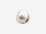 a white pearl on a white surface with a silver object in the middle
