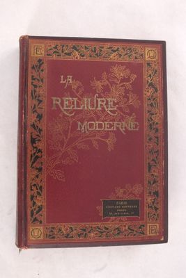 un vieux livre à la couverture rouge posé sur une surface blanche