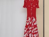 La robe est rouge et blanche, avec des fleurs blanches dessus.
