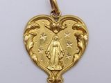 a close up of a gold heart shaped pendant on a white surface
