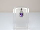 a close up of a purple and white diamond pendant on a clear display case