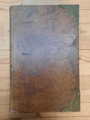 un vieux livre posé sur une table en bois, sur un parquet