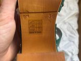 someone is holding a pair of brown shoes in a box