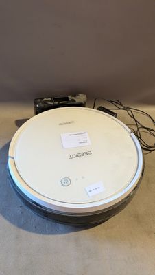 un robot blanc posé par terre à côté d'une télécommande