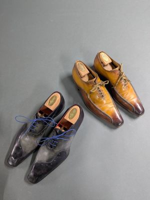 two pairs of men ' s shoes sitting on a table next to a pair of shoes