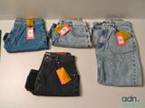 five pairs of jeans sitting on a table next to a cell phone