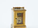 a gold clock that is sitting on a white surface