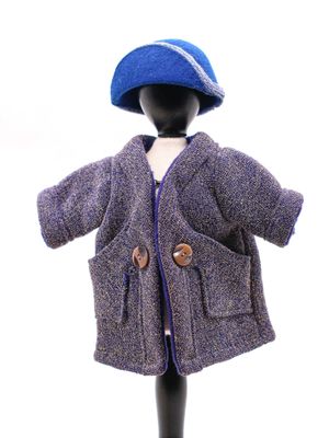 poupée vêtue d'un manteau violet et d'un chapeau bleu, posée sur un mannequin noir