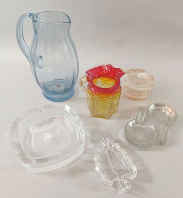 a glass pitcher, a bowl, and other glass items on a table