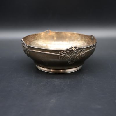 silver plated bowl on a black surface with a black background