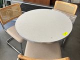 a table with four chairs and a plant in the background