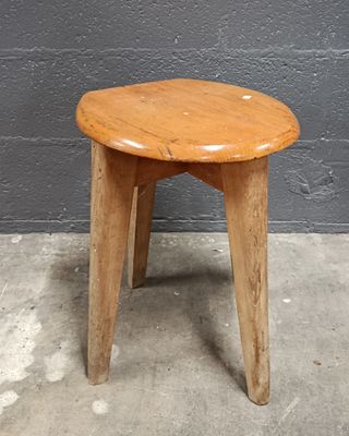un petit tabouret en bois posé sur un sol en béton