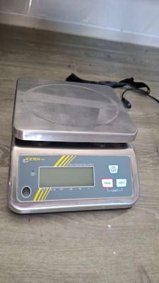 a digital scale sitting on the floor next to a charger