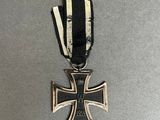 a close up of a metal cross with a black and white ribbon