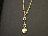 un collier en or auquel est suspendu un pendentif en forme de cœur