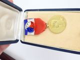 a gold medal with a red, white, and blue ribbon in a box