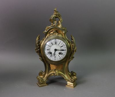 une petite horloge en or surmontée d'un oiseau