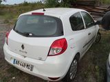 a small white car parked next to a pile of wood