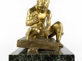 bronze statue of a boy sitting on a rock holding a baby
