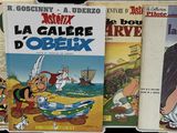 quatre albums de bande dessinée sont alignés les uns à côté des autres sur un fond noir