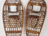 pair of antique snowshoes with wooden handles and straps