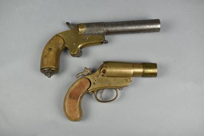 deux vieux revolvers posés sur une surface blanche, accompagnés d'un porte-clés