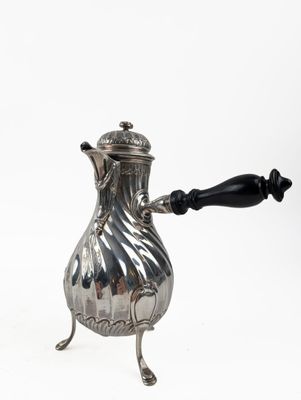 an antique silver coffee pot on a stand with a black handle