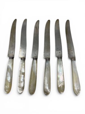 five knives are lined up in a row on a white surface
