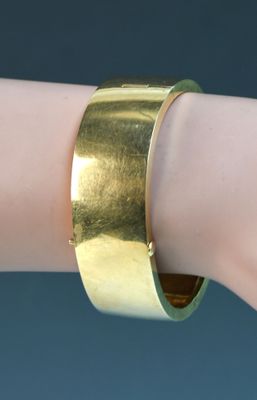un bracelet manchette plaqué or au poignet d'une femme