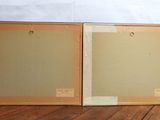 pair of two framed paintings on a wooden surface