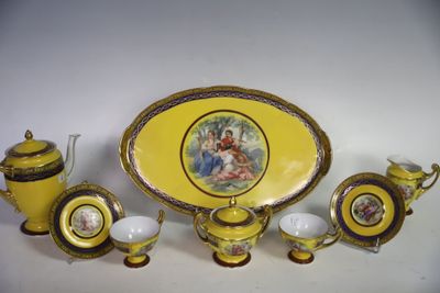 une assiette jaune ornée d'une image, posée à côté de tasses et de soucoupes