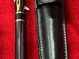 un stylo noir et un étui noir posés sur un tissu rouge