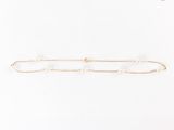 un bracelet en chaîne dorée orné de perles sur fond blanc