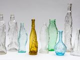 many different colored glass bottles lined up on a white surface