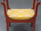 une image représentant un banc en bois dont l'assise est recouverte d'un tissu jaune et rouge