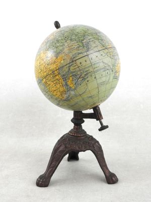 un petit globe posé sur un socle, sur une surface blanche